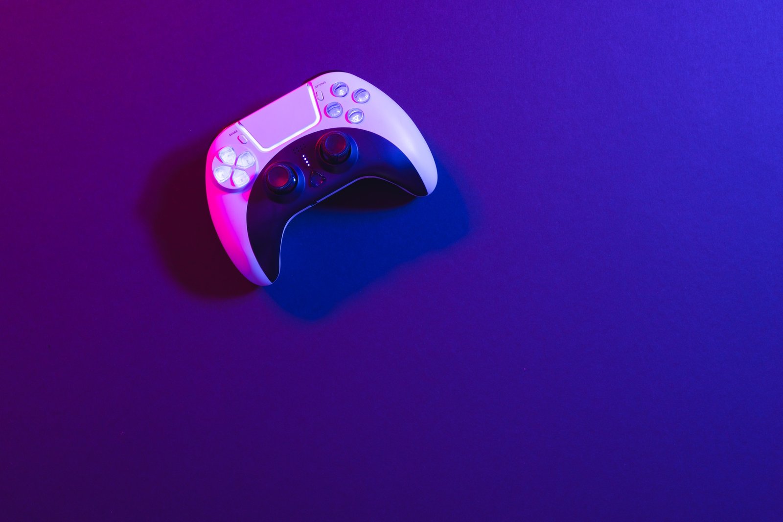 Composite of video game pad and copy space on neon background